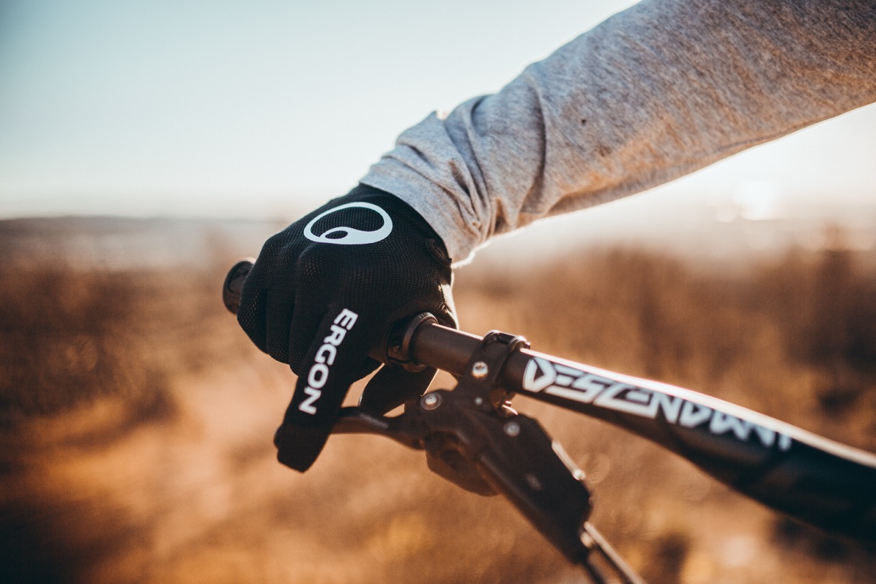 Close-up of bicycle handlebars with hand on handlebars, focus on Ergon HM2 gloves. 