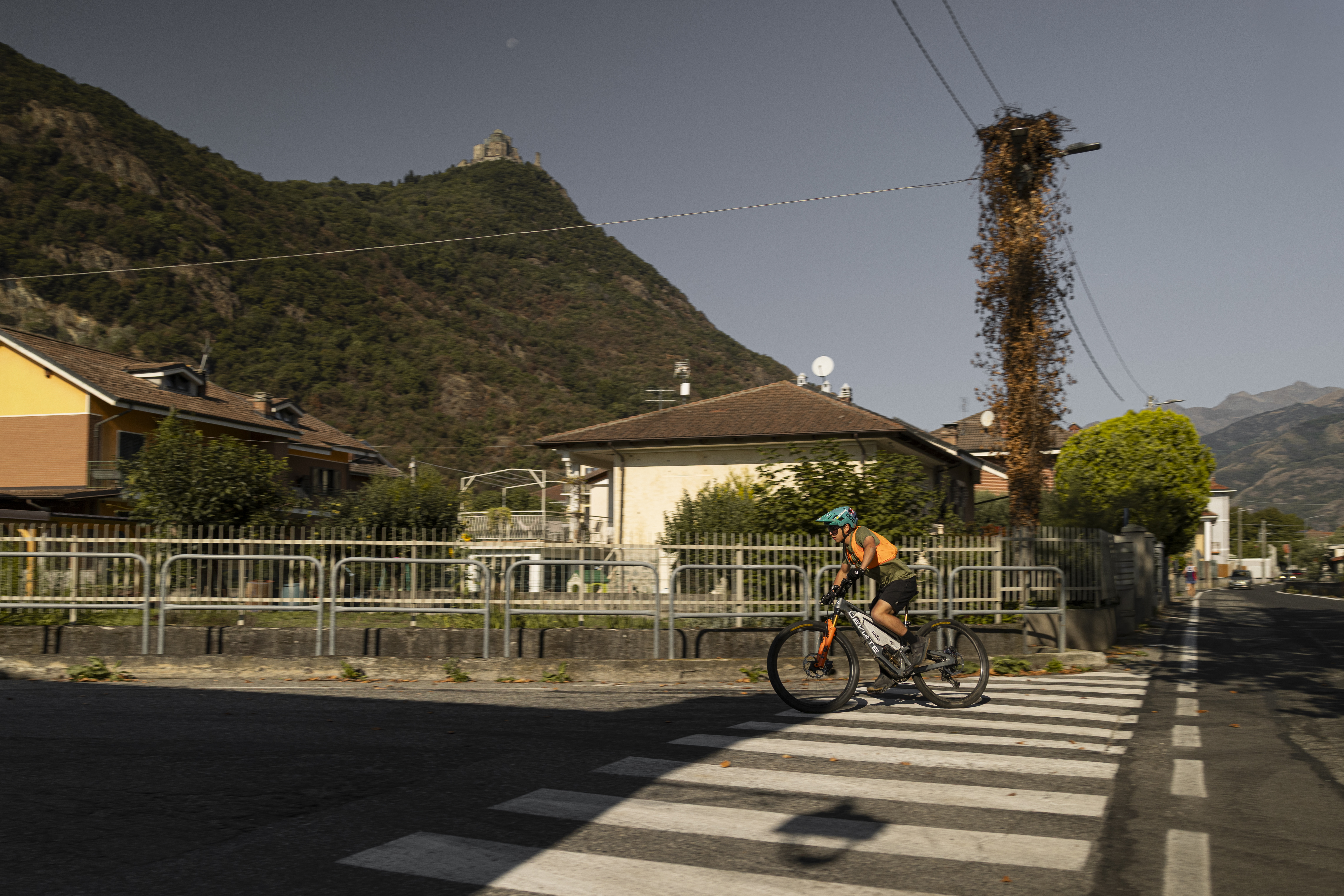 Matthew Fairbrother rides his bike with Ergon saddle and grips through an Italian village, with a hill and castle in the background.