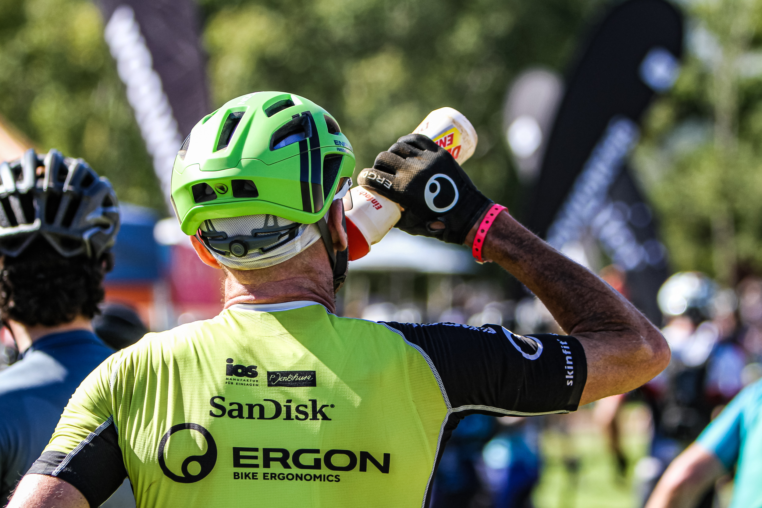 Ergon Radsportler Westsiders Ergon Radsportler mit grünem Helm trinkt aus einer Flasche bei einem Event.