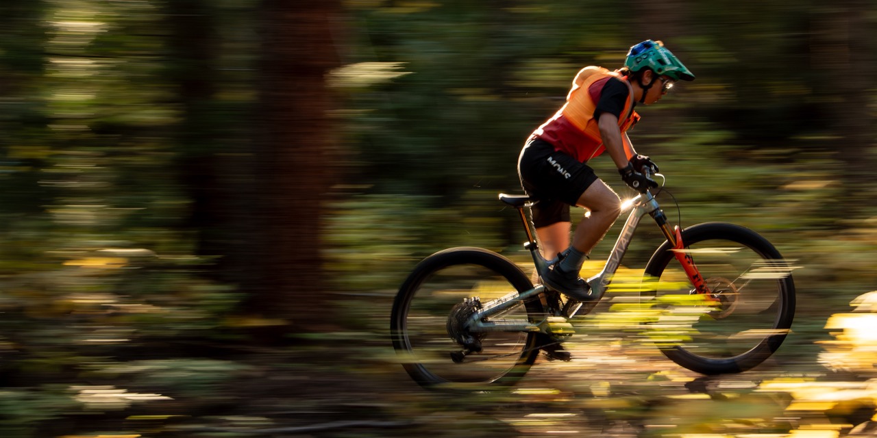 Matthew Fairbrother fährt mit dem Fahrrad schnell über einen Waldweg.