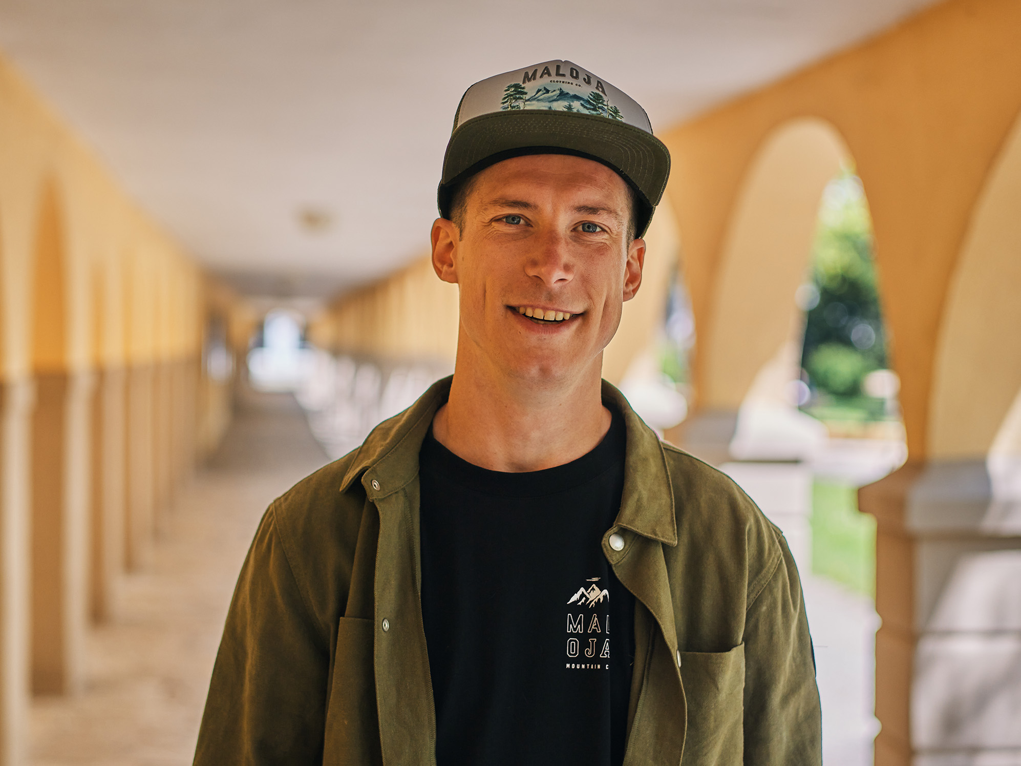 Portrait of Jasper Jauch smiling, wearing a baseball cap and a green shirt.