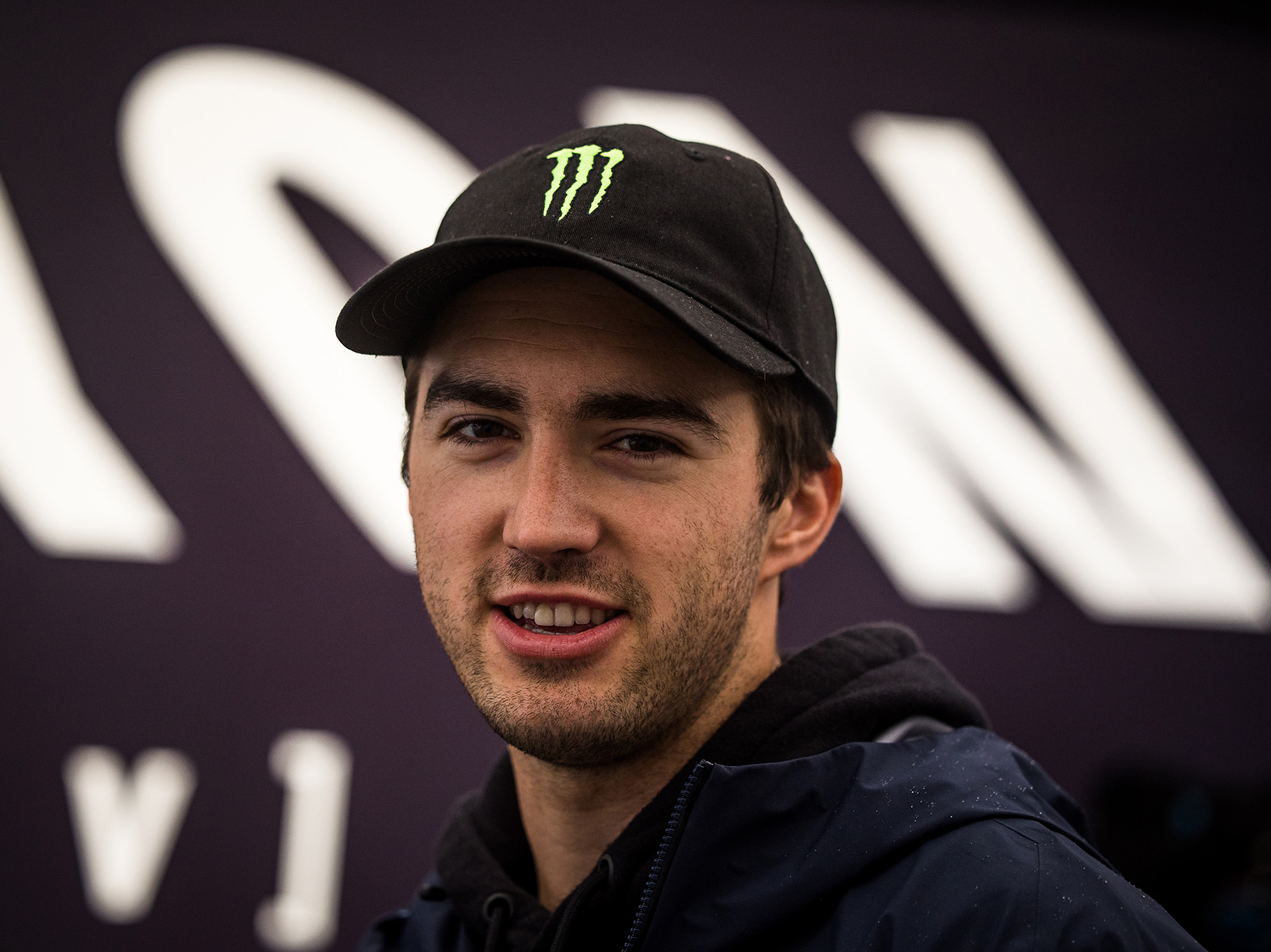 A slightly angled portrait of Luca Shaw smiling and wearing a baseball cap.