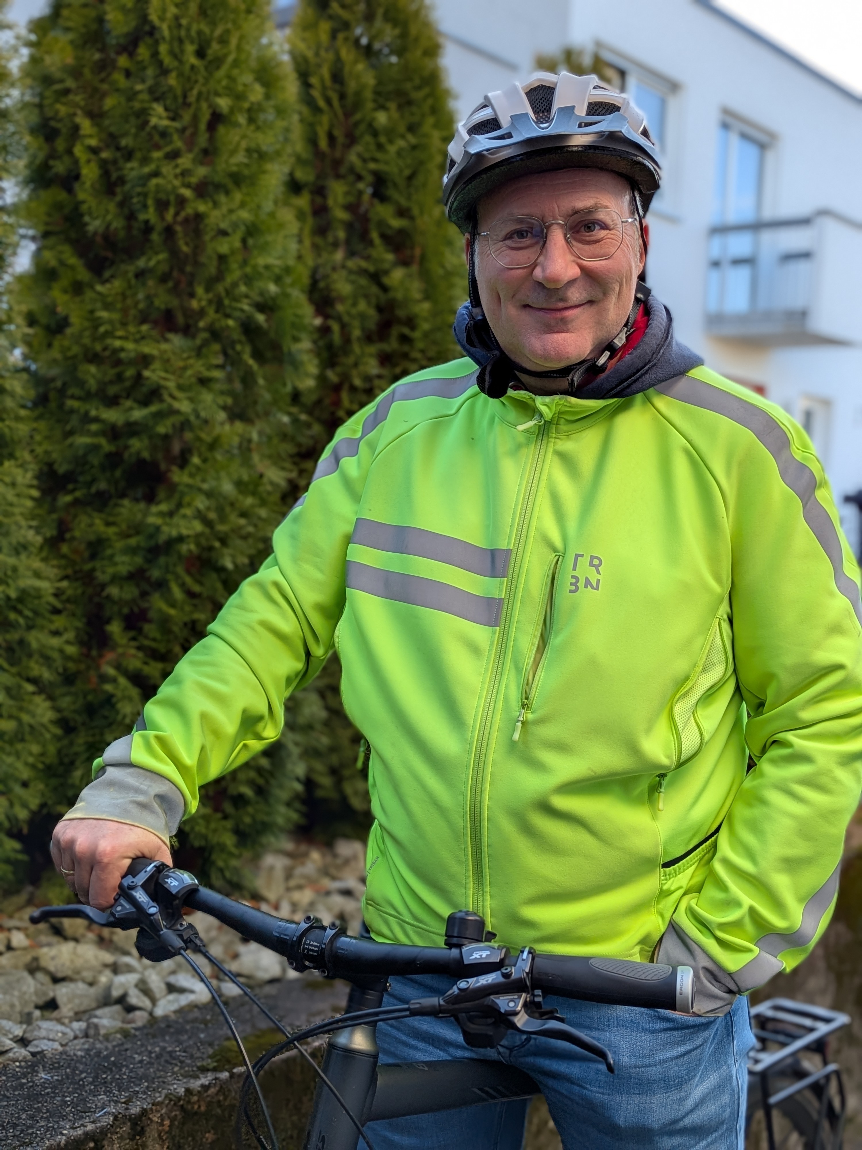 Porträt von Jochen Schniepp, der mit seinem Fahrrad samt montierter GP1 Evo Griffe und einer geleben Warnweste seine Zufriedenheit zeigt.
