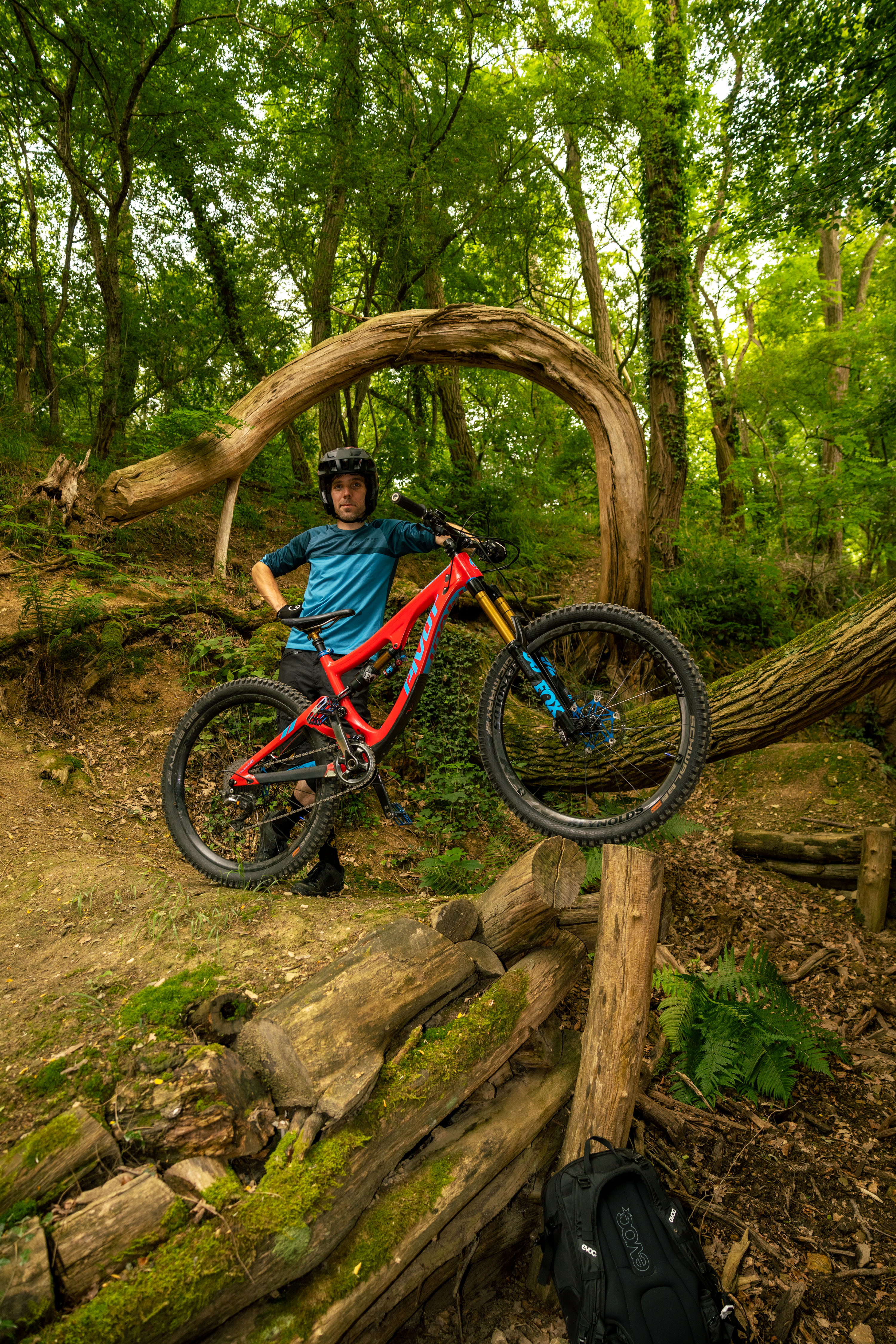 Freeride mountain biker balancing on logs and technical wooden features in a forest section of Bikepark Bendorf.