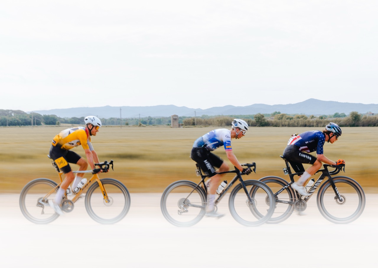 Three gravel racers are riding in single file at the Traka