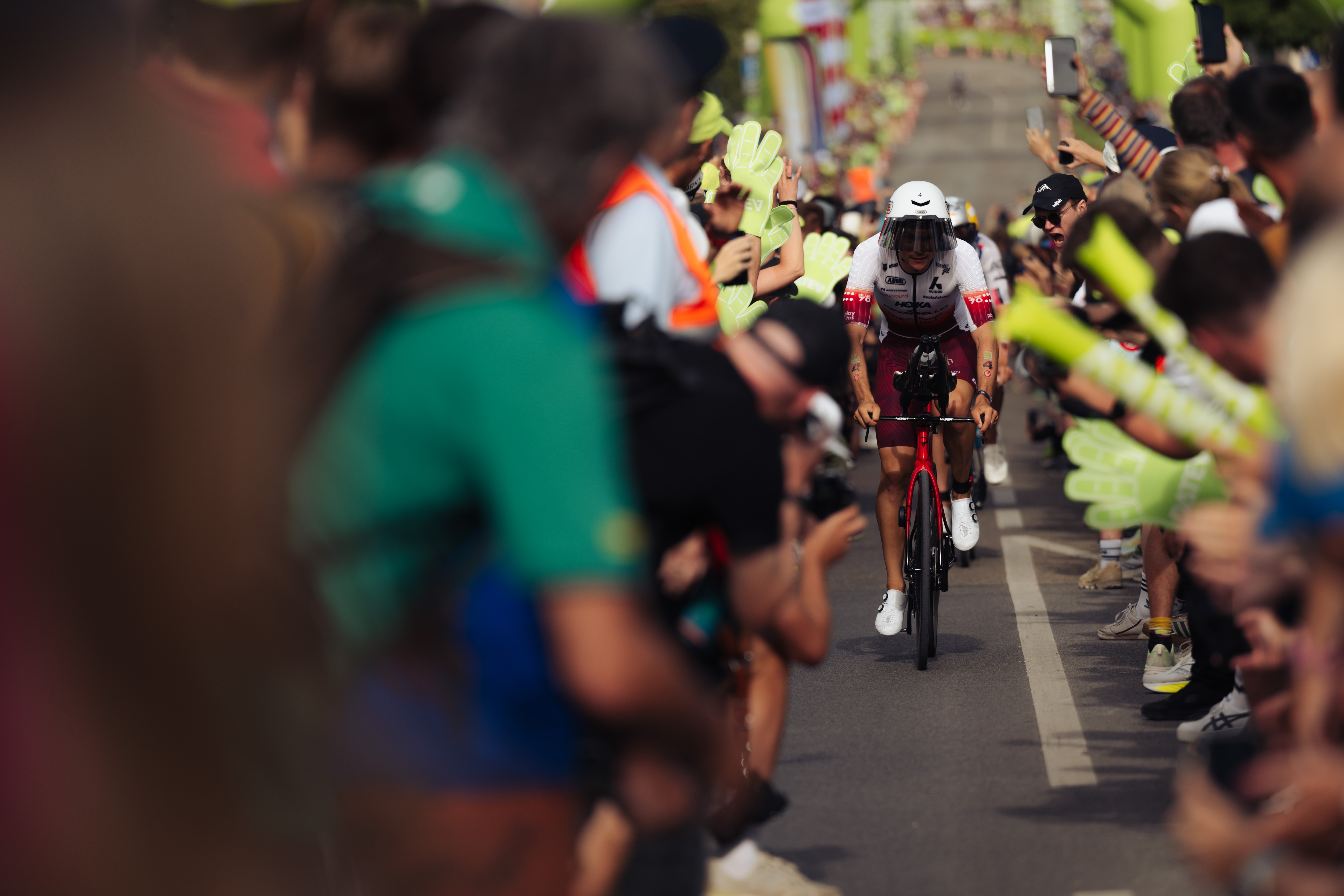 Triathlet fährt mit dem Fahrrad durch eine dichte Zuschauermenge