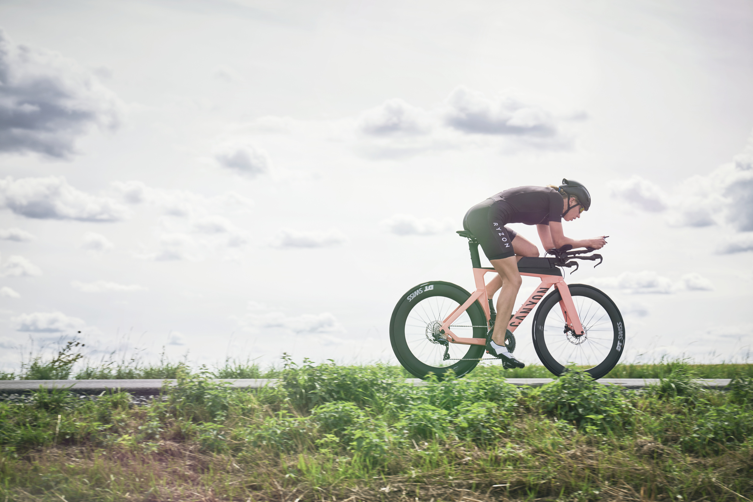 Frau fährt mit Triathlonrad über eine asphaltierte Straße
