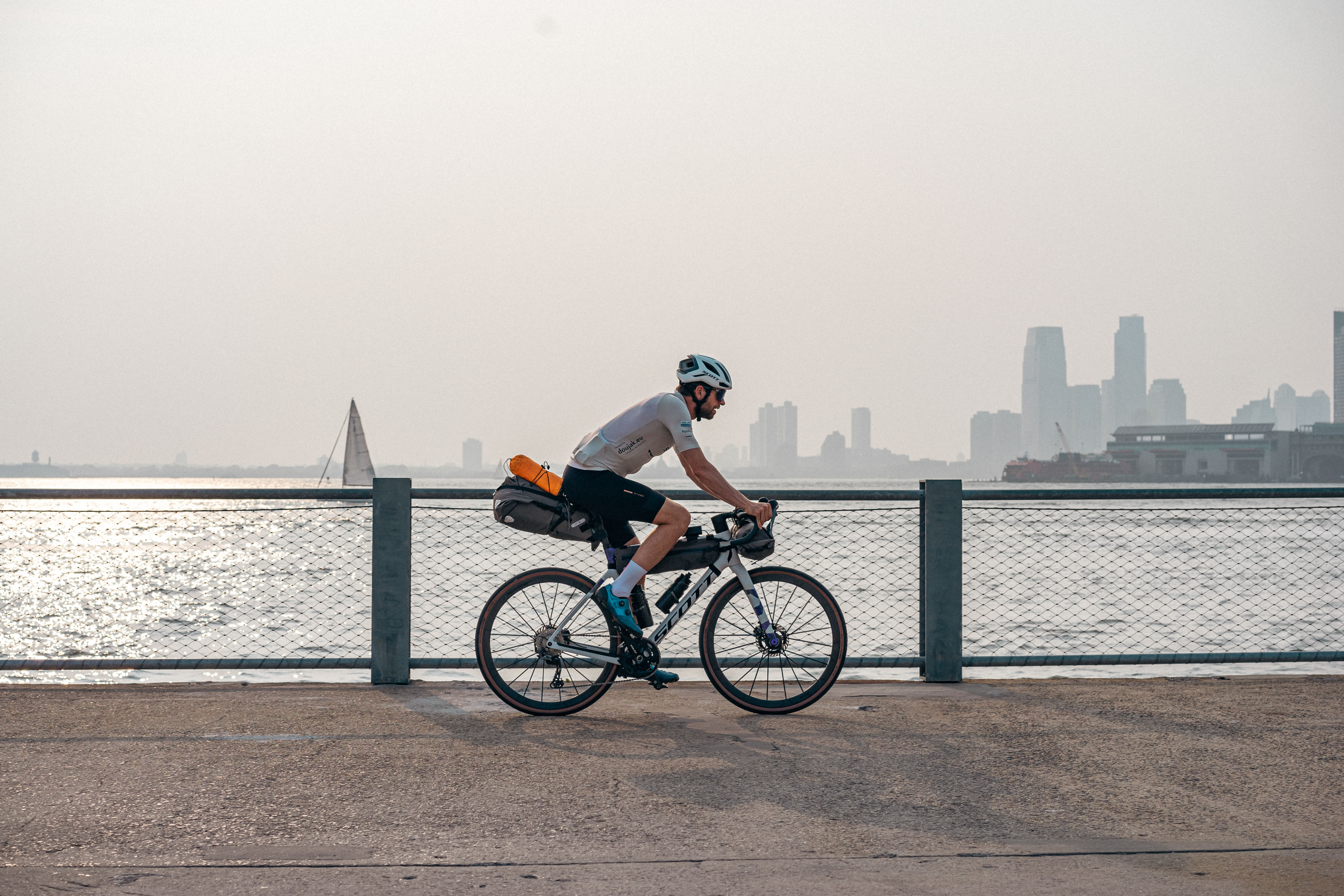 Mann fährt mit Bikepacking Rad am Wasser entlang.