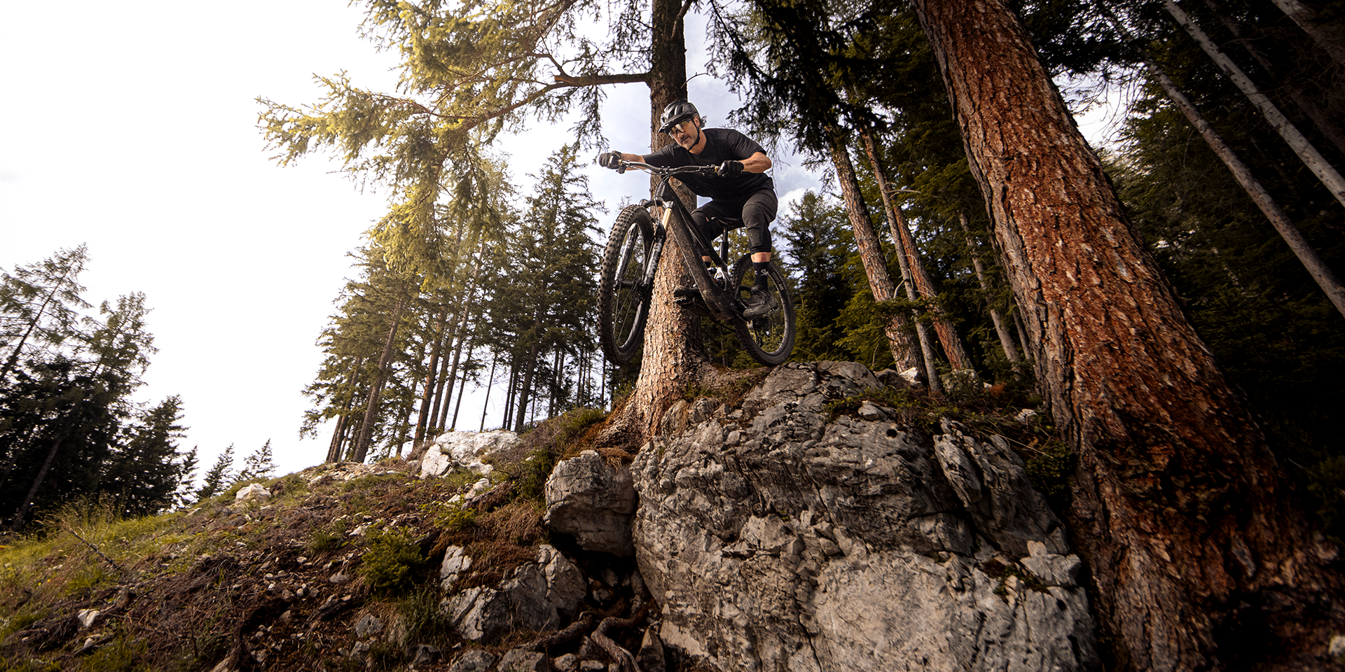 Mountainbiker mit Ergon GMA Griffen springt über ein Felsstück im Wald