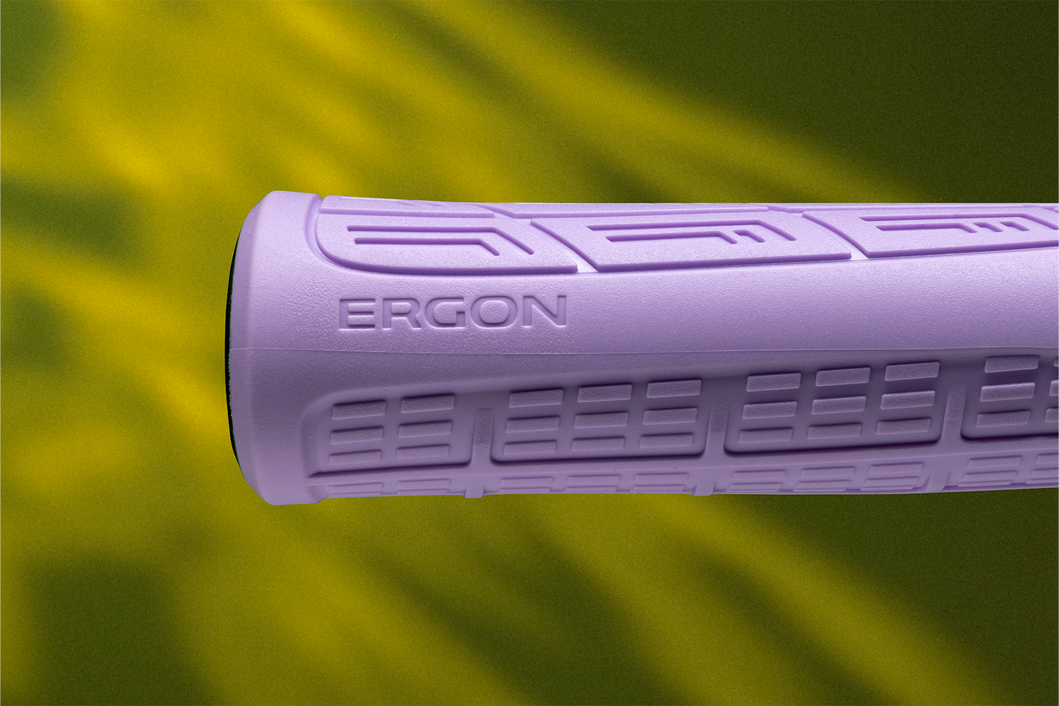 Nahaufnahme des Ergon GMS Griffs in Flieder vor grünem Hintergrund