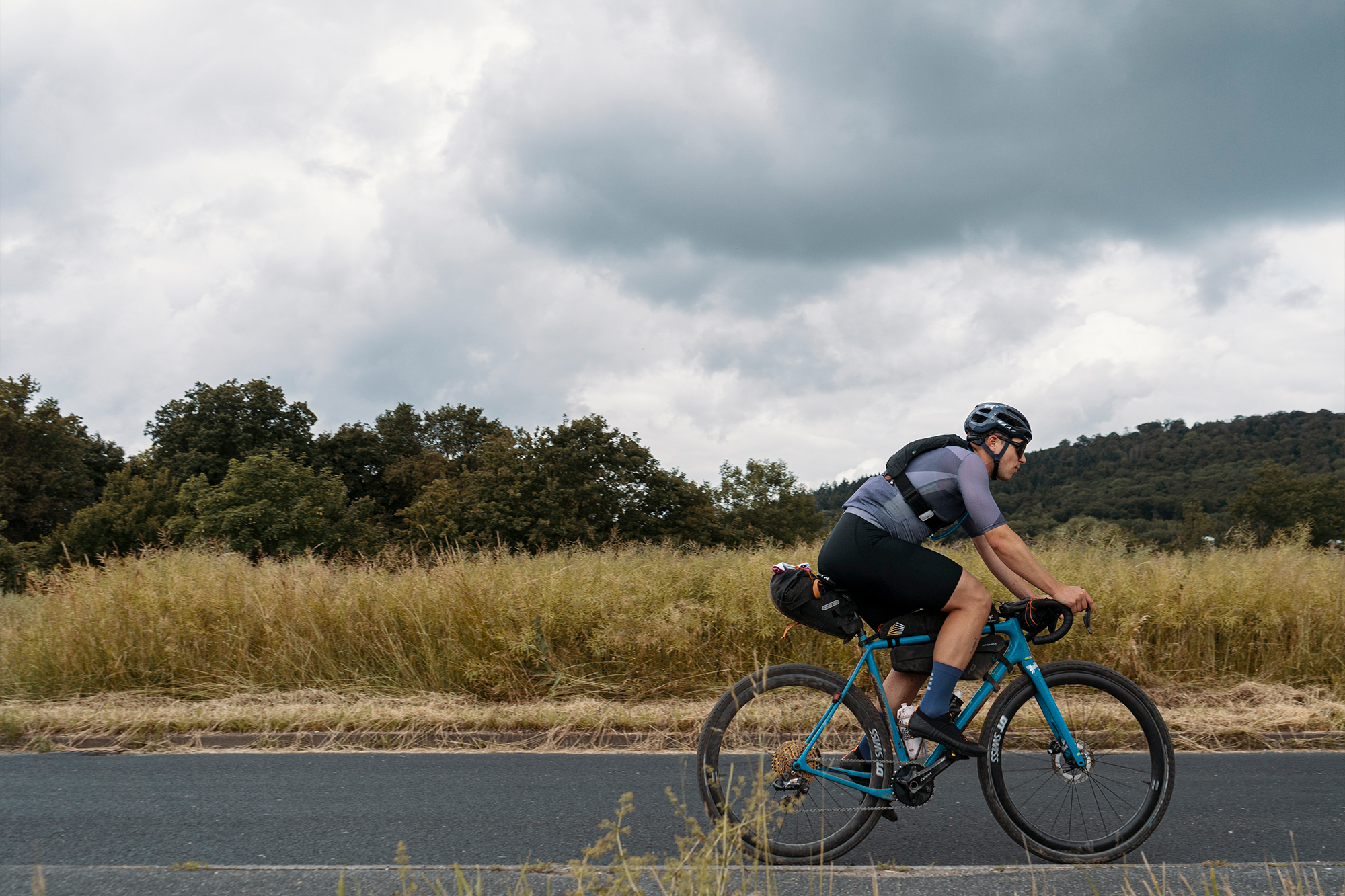 Cyclist rides along a country road through open countryside under a cloudy sky
Photographer Jakab Rokob