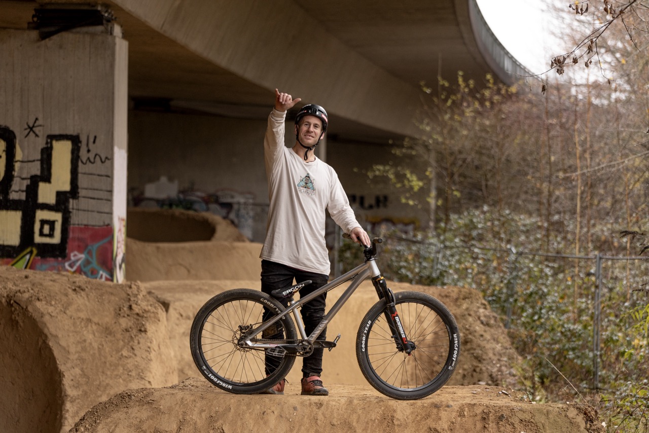 Sam Pilgrim steht mit seinem Fahrrad auf einer Rampe im Dirtpark