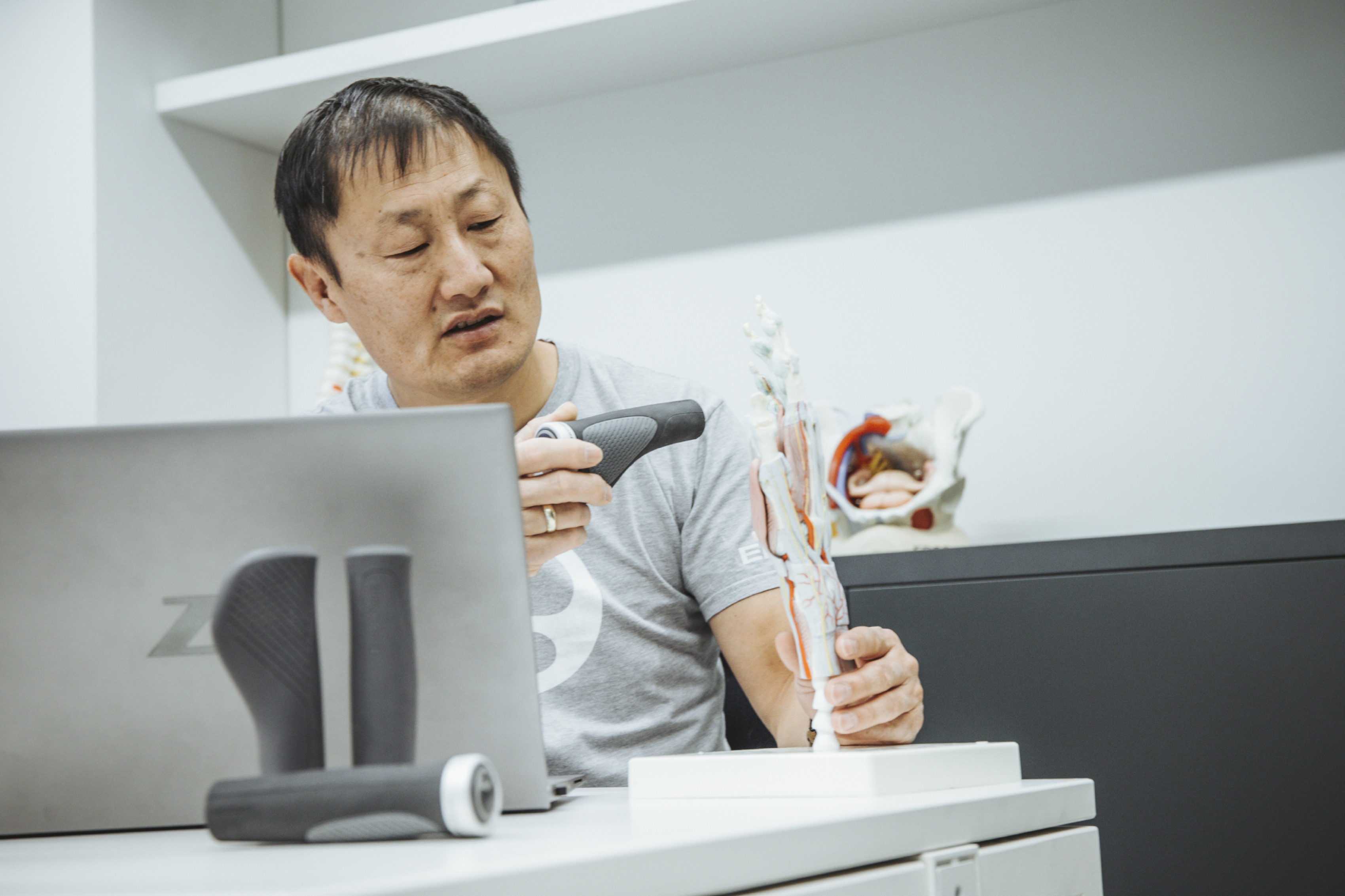 Kim Tofaute, Ergonomist at Ergon, at his desk with laptop presenting the GP1 on a bone model of a hand