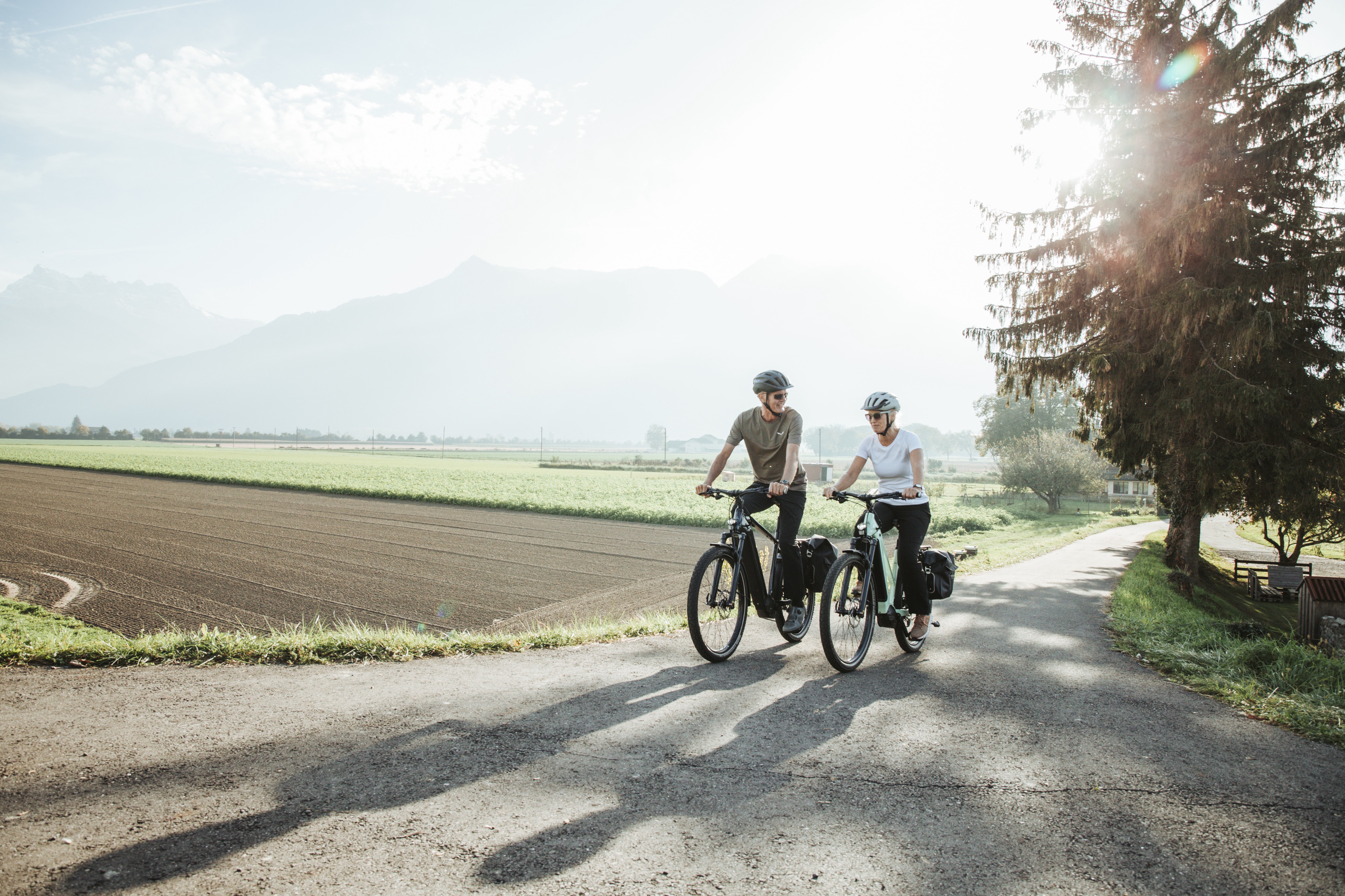 Zwei Radfahrer auf Landstraße mit Bergkulisse