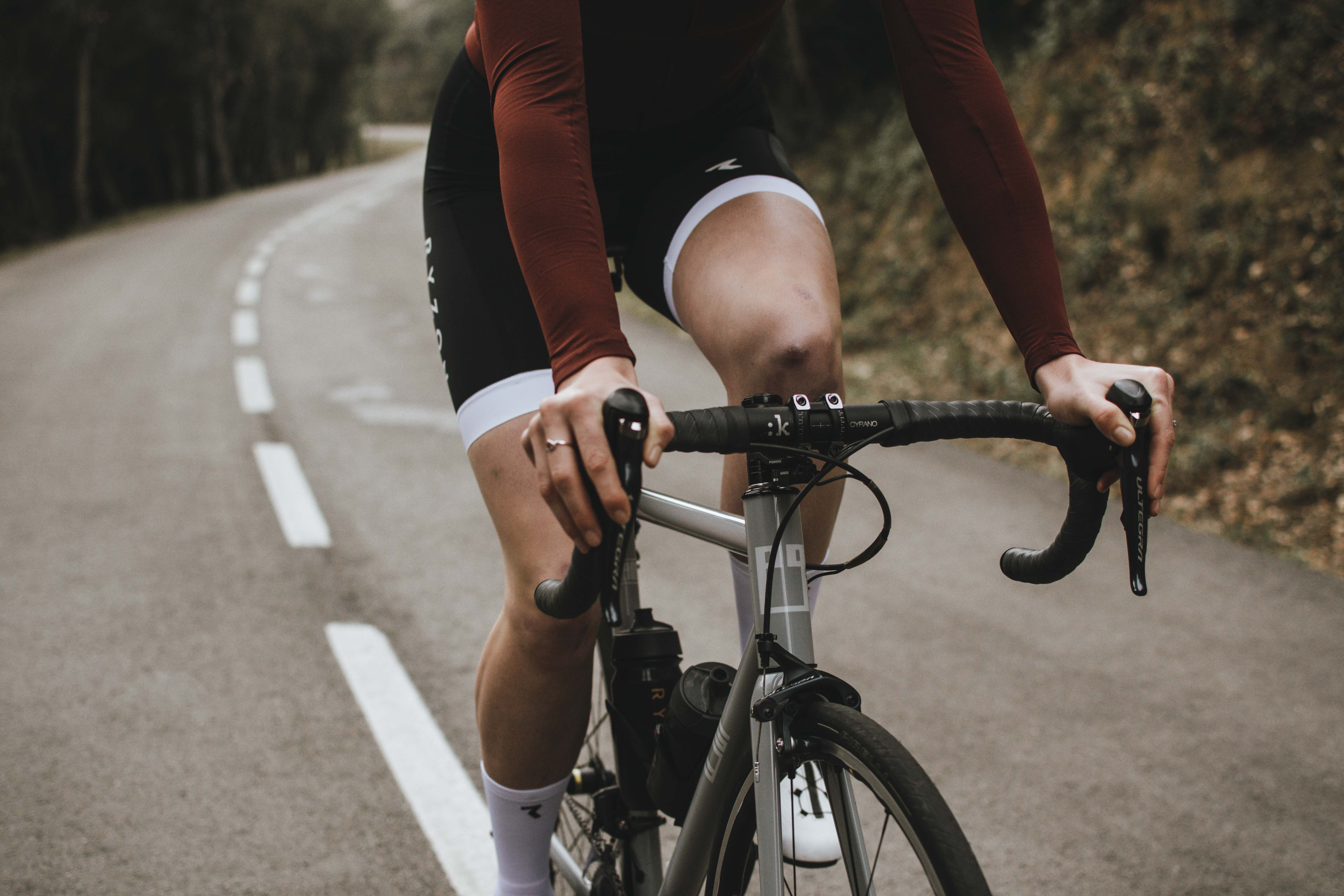 Detail eines Rennradfahrers in Aktion, der auf einer einsamen Straße mit dem ergonomischen BT Road Black Lenkerband fährt