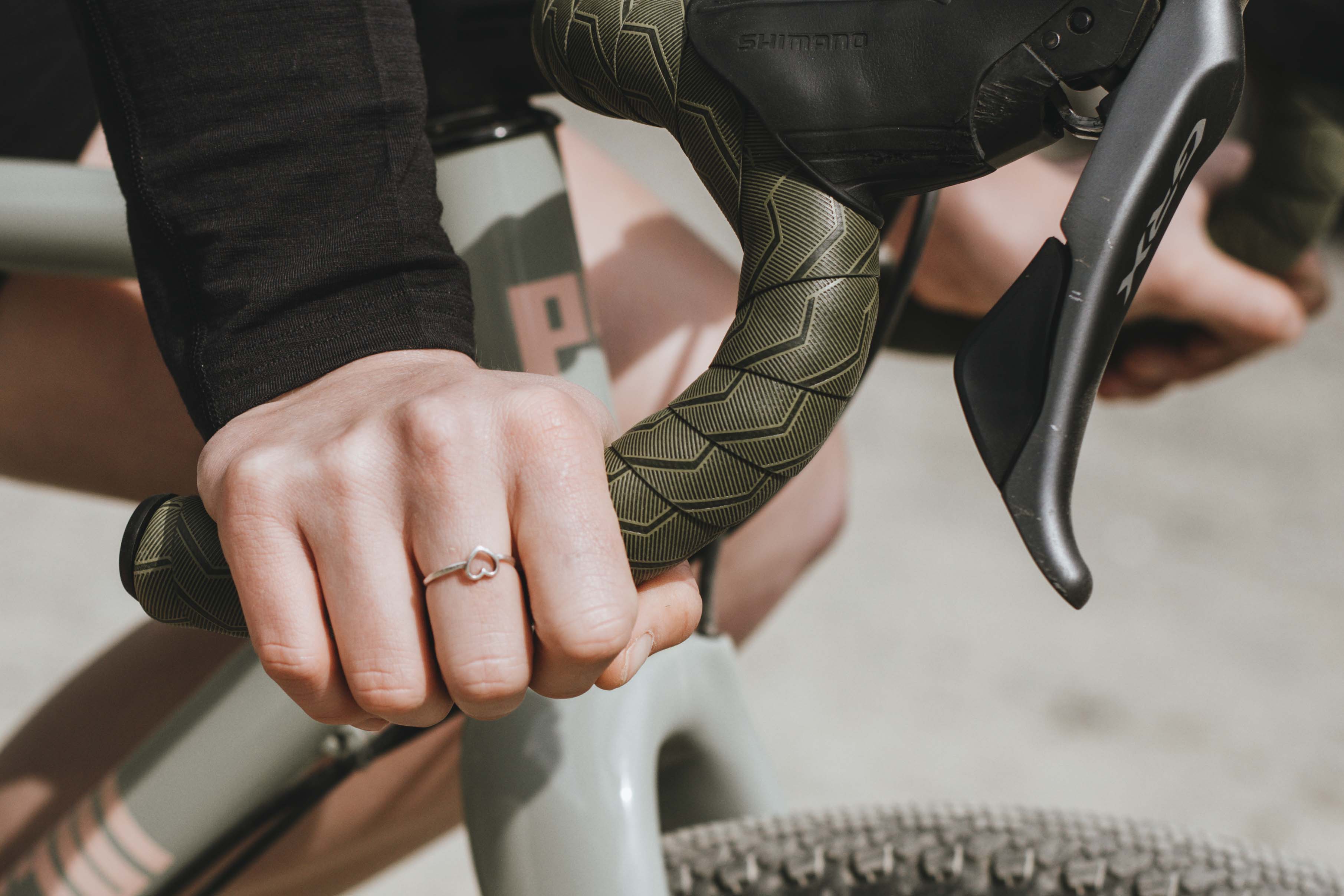 Nahaufnahme einer Frauenhand am unteren Lenker mit Ergon BT Gravel Lenkerband in Swap Green in Aktion.