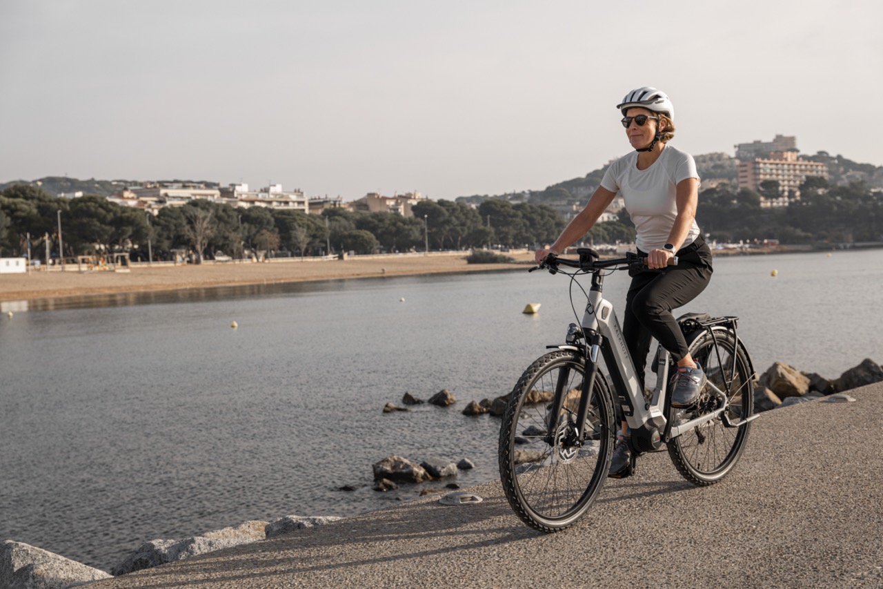 Frau fährt mit dem Fahrrad am Fluss entlang.