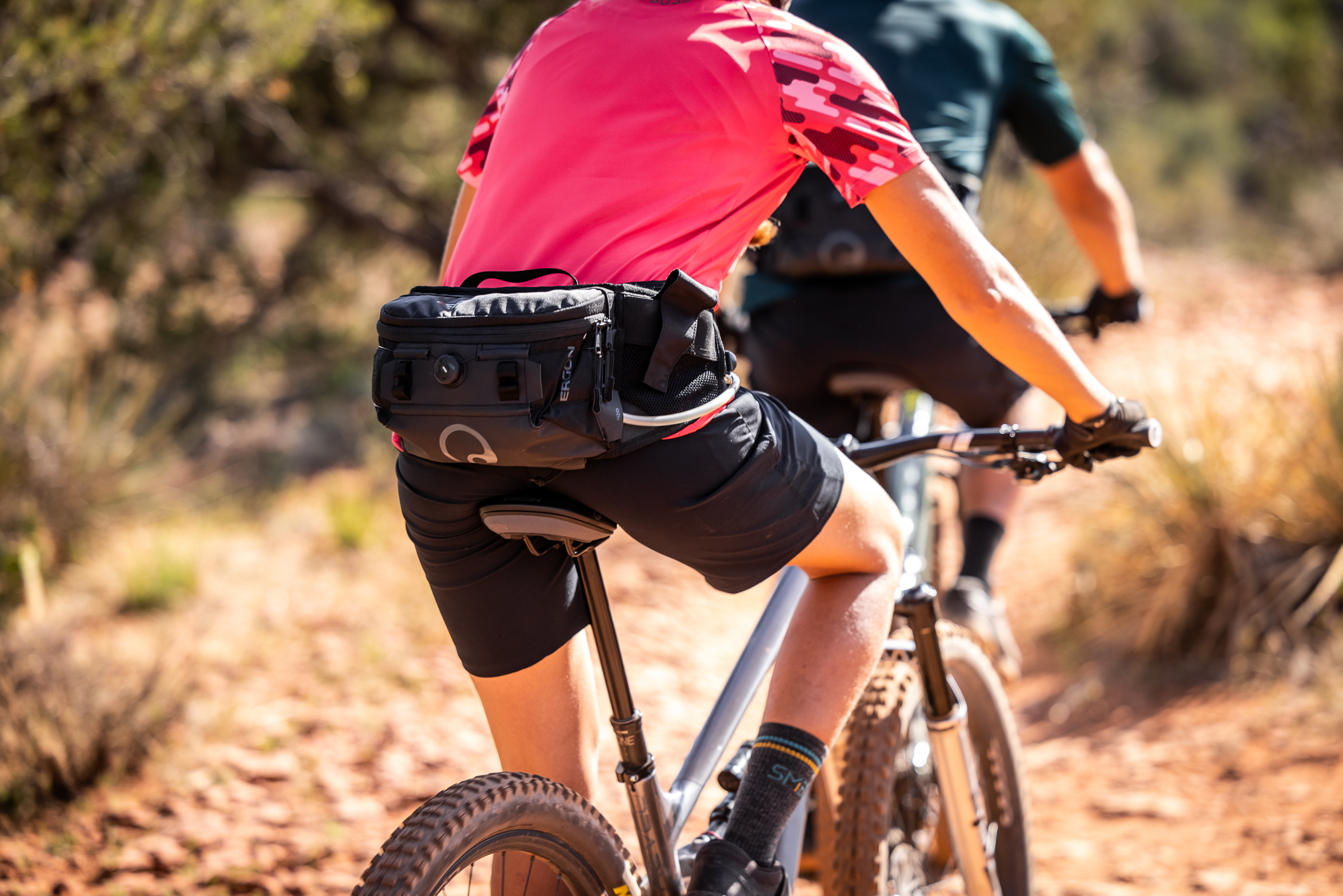 Frau fährt auf einem MTB. Nachaufnahme auf die Radhose. Sie trägt ein Ergon BA Hip Pack.