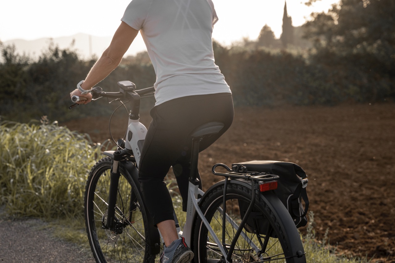 Frau sitzt auf Tourenrad. Nahaufnahme von hinten.