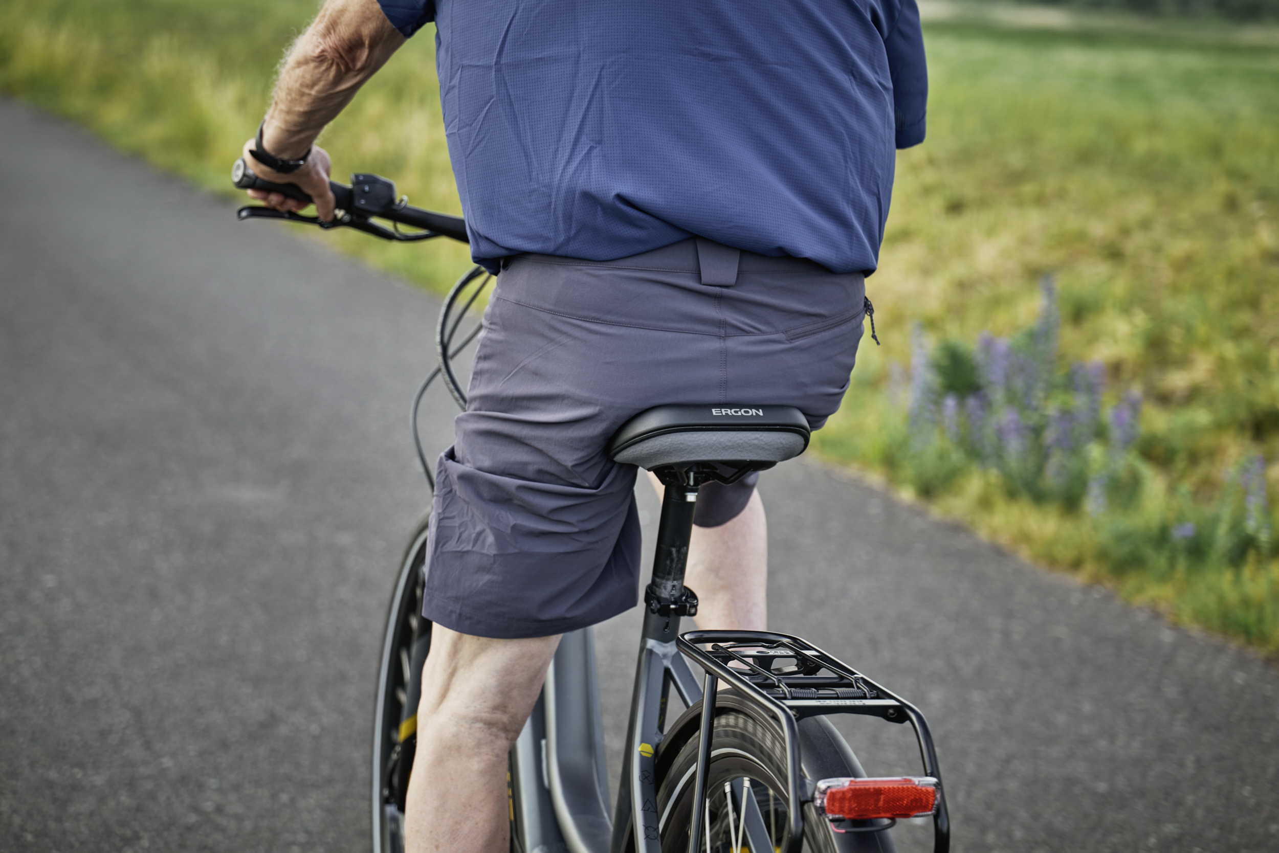 Mann sitzt auf Tourenrad. Nahaufnahme von hinten.