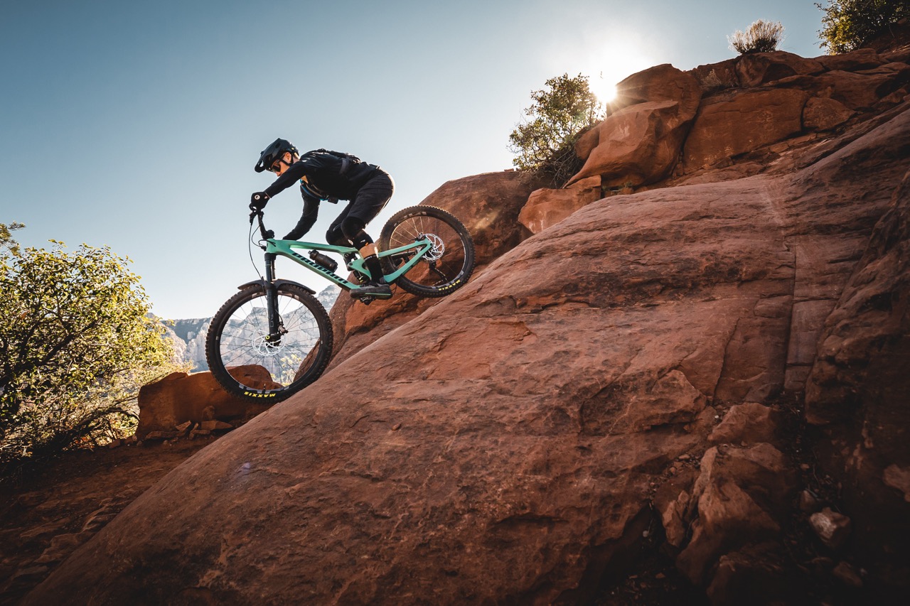 A man rides down a field slope on his MTB.