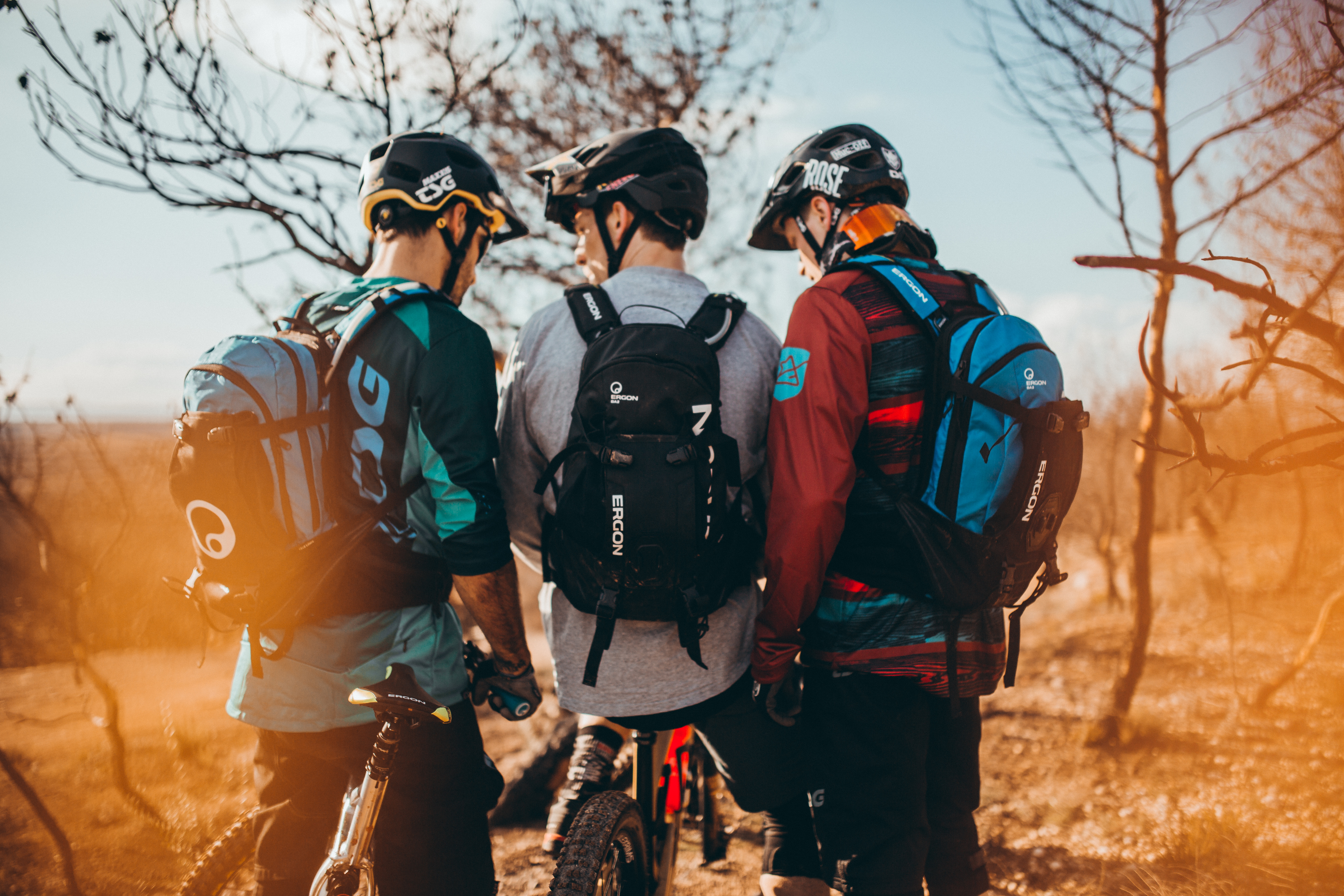 3 MTB Fahrer stehen zusammen, alle tragen Rucksäcke
