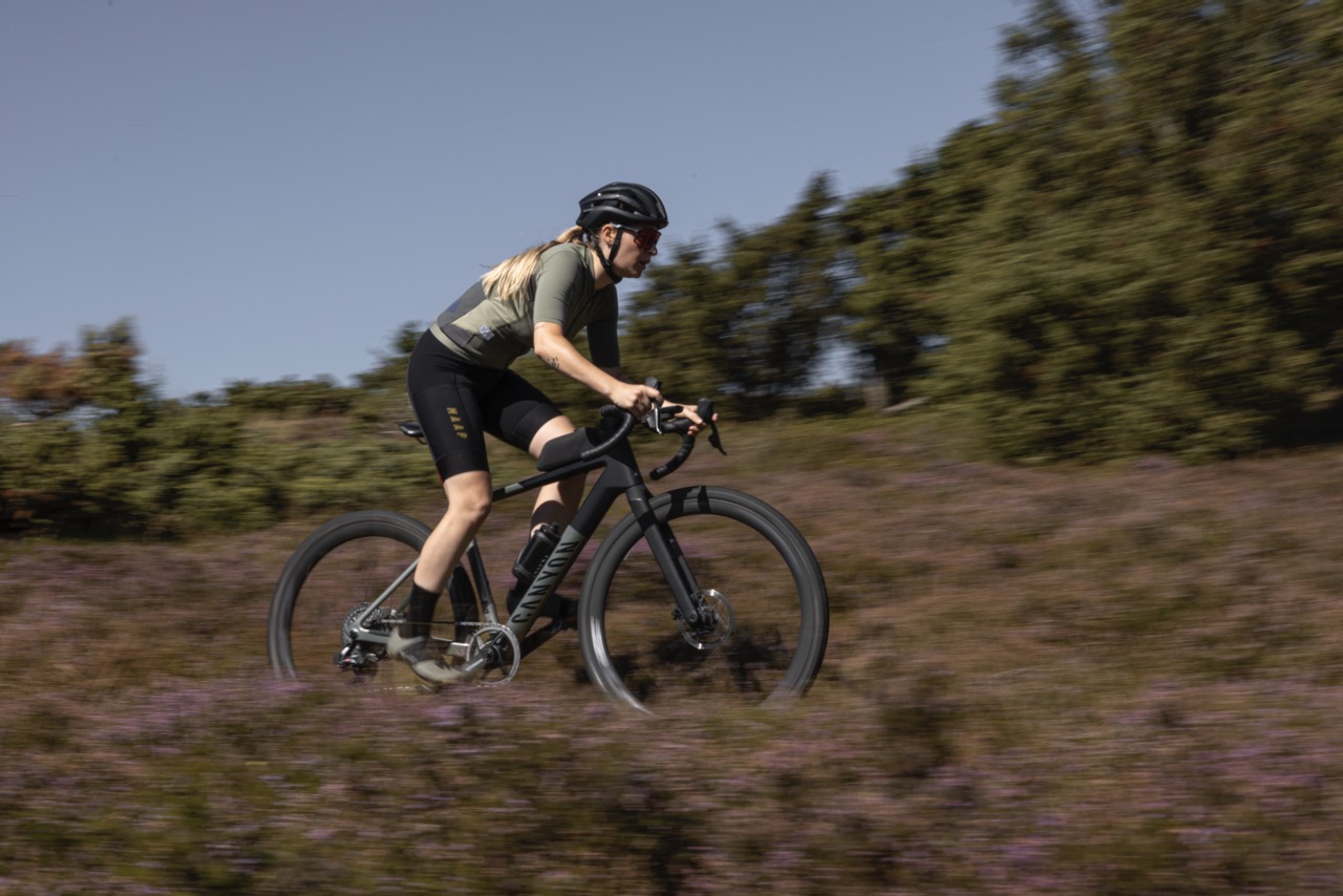 Frau fährt mit Gravelbike durch Gelände
