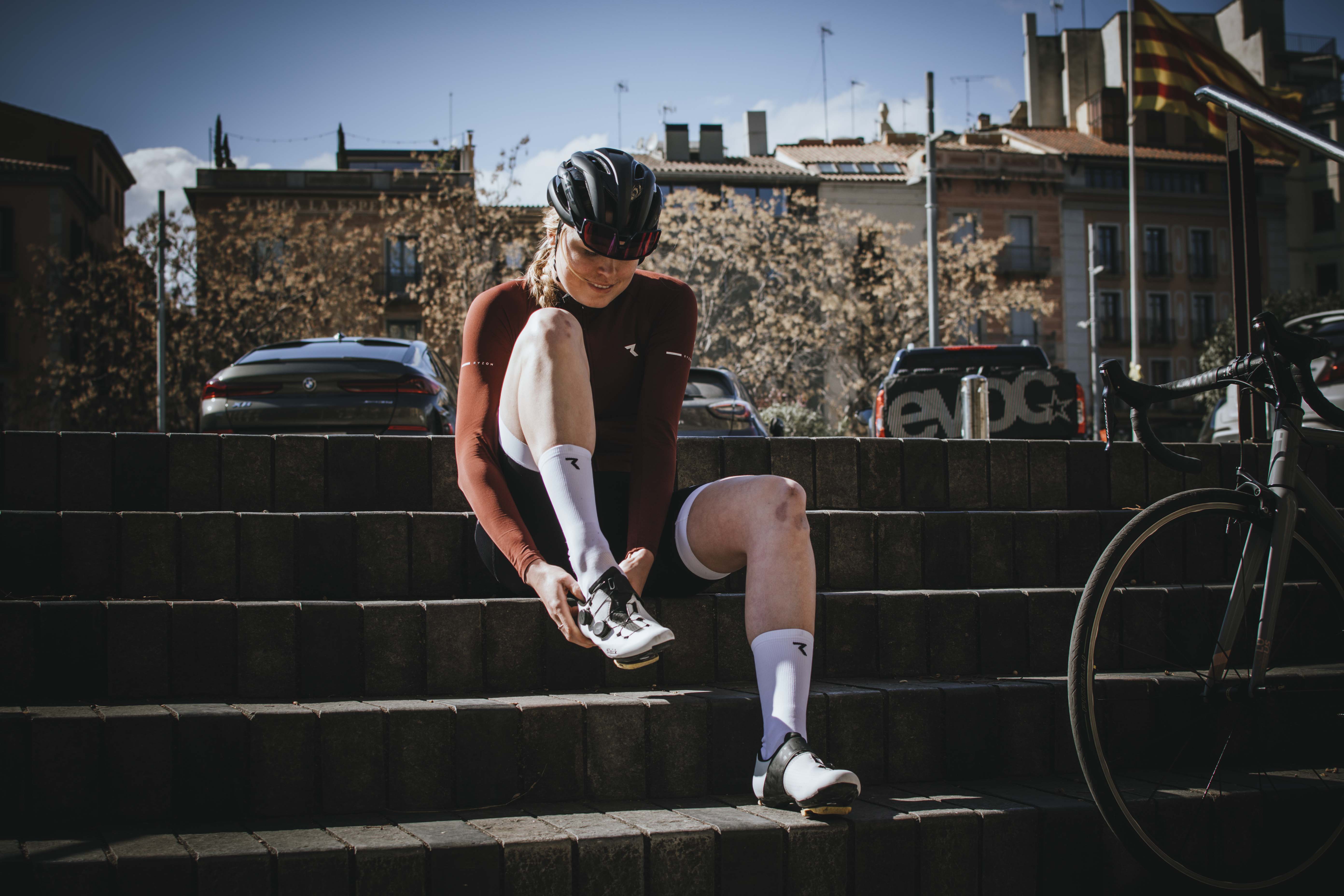 Fahrradfahrerin zieht Radschuhe auf einer Treppe an.