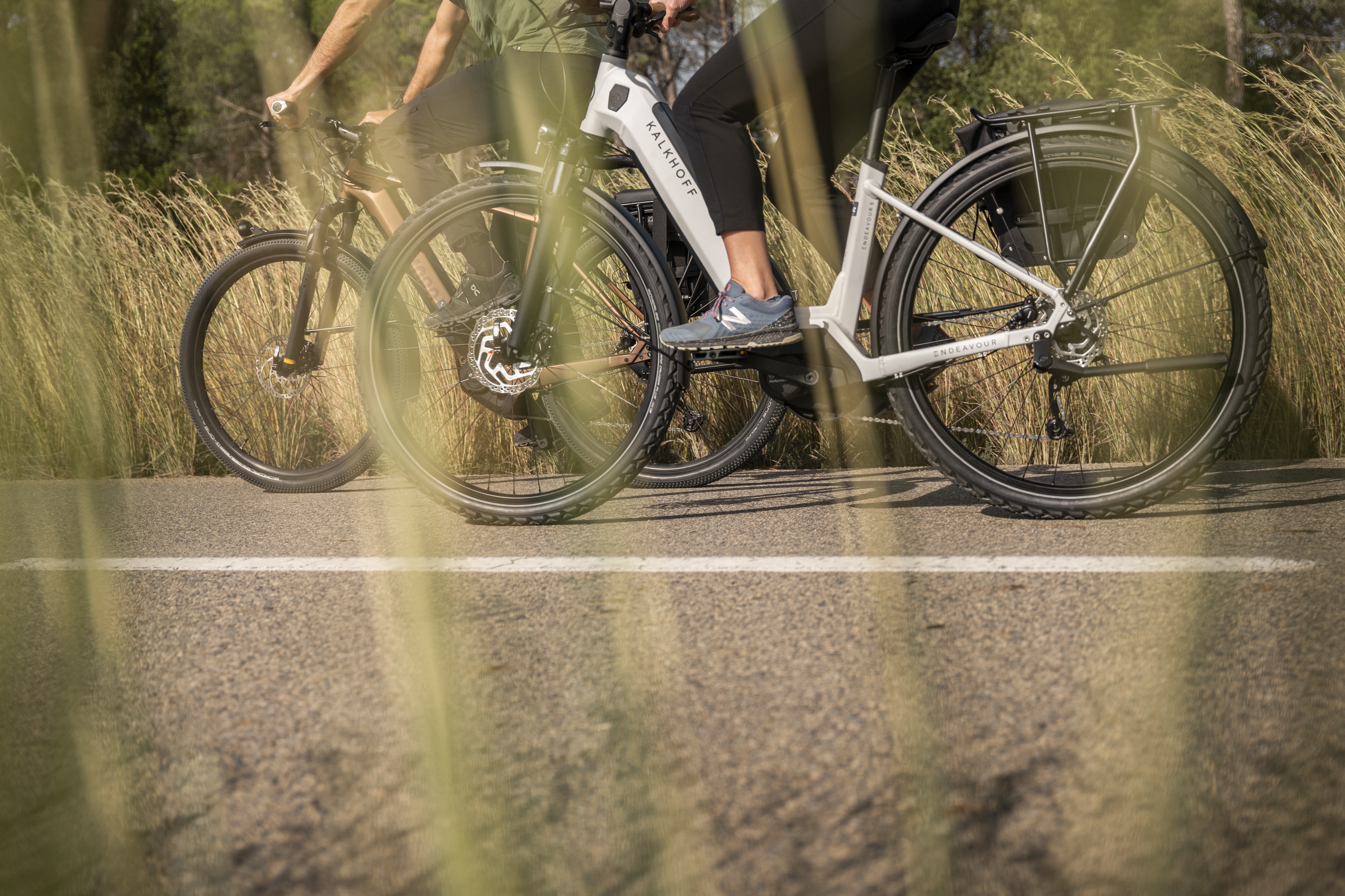 Zwei Radfahrer auf E-Bikes auf einer Straße.