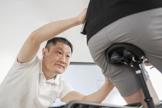 Kim Tofaute bei der ergonomischen Anpassung eines Radfahrers Kim Tofaute, Ergonom bei Ergon, führt eine ergonomische Analyse durch und überprüft den Hüftwinkel eines Radfahrers während einer Sitzpositionsanpassung.
