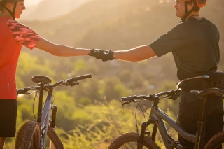Zwei Mountainbiker geben sich einen Faustgruß in der Wüste und tragen Ergon HM2 Handschuhe. 