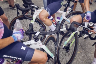 Ergon Nutrition Cycling Canyon SRAM Team Female cyclists in a race, close-up, focus on dynamic movement and beverages.