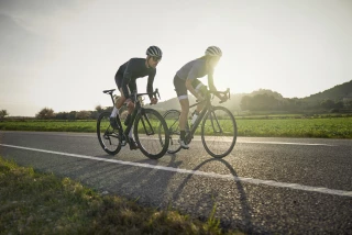 Ergon stretching exercises and stretching for cyclists Two road cyclists riding on a country road at sunset